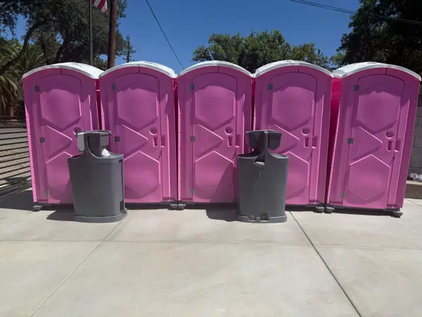 Row of pink portable toilets with two hand wash stations