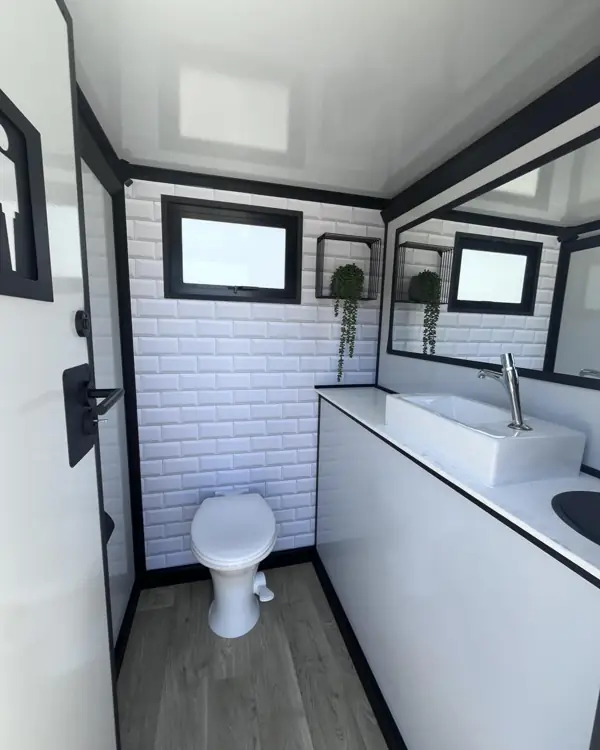 Restroom trailer stall with flushing toilet and sink