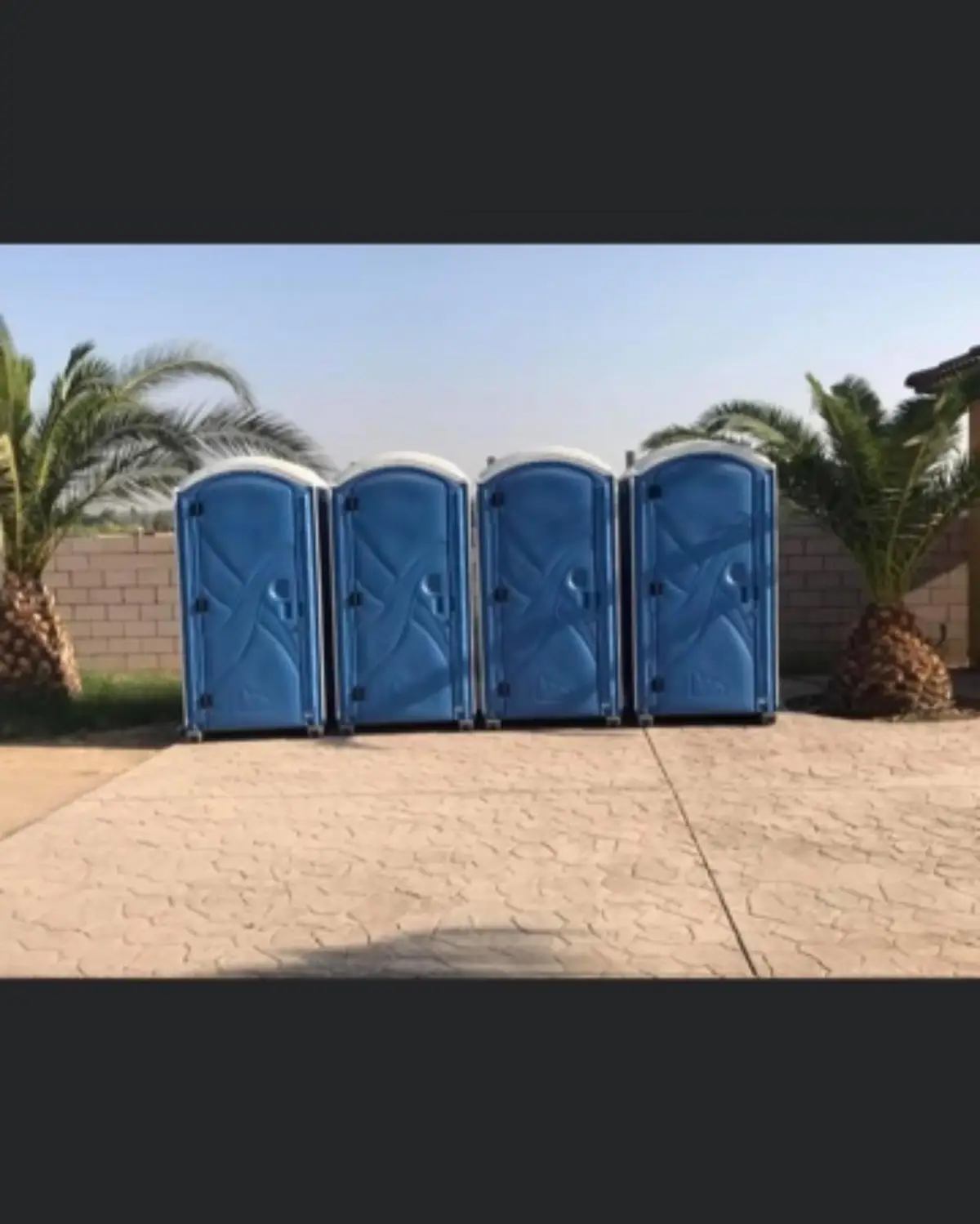 A row of blue portable toilets lined up on a paved event lot
