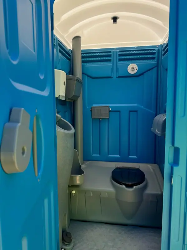 Interior of a standard porta potty with urinal, seat and toilet paper holder