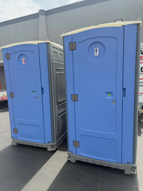 Two blue portable toilets just delivered on a paved lot