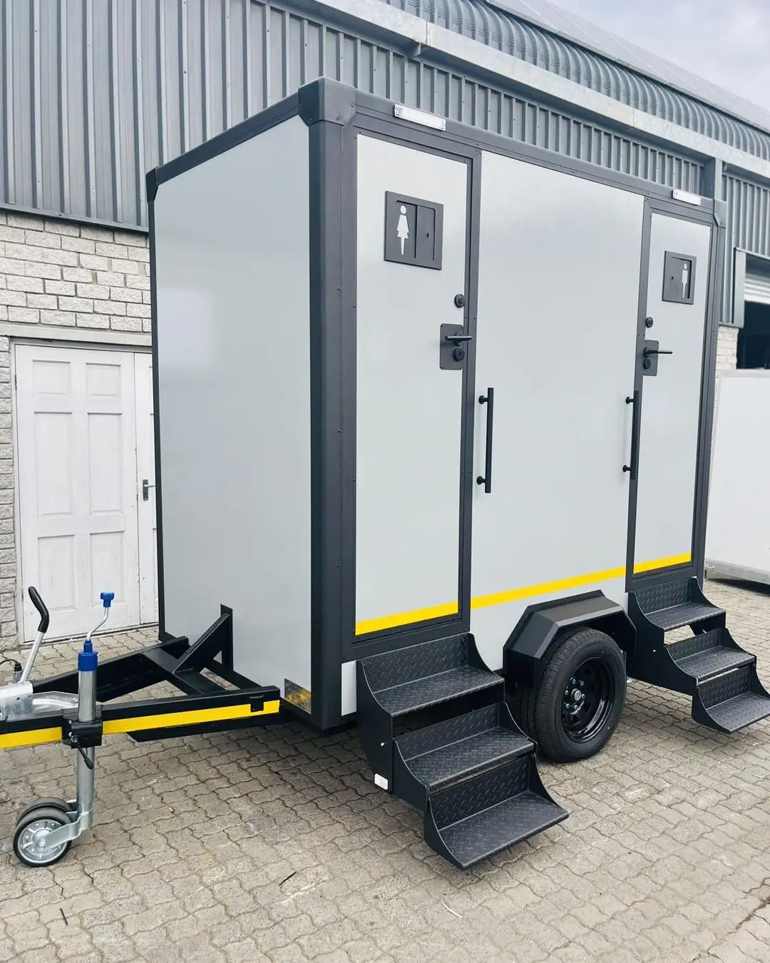 White two-stall restroom trailer with separate doors and entry steps